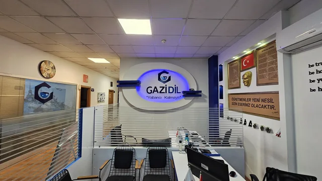 GaziDil duvar logosunun önünde danışma masası ve bekleme koltukları