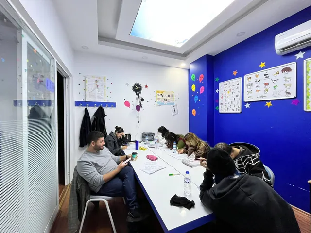 GaziDil’in cam bölmeli ders odasında uzun masa çevresinde çalışan katılımcılar